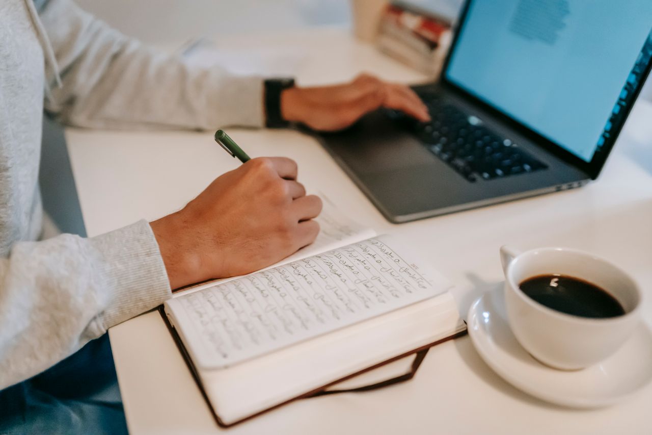 Persona con un computador, un cuaderno y una pluma, evaluando que curso vender en systeme.io