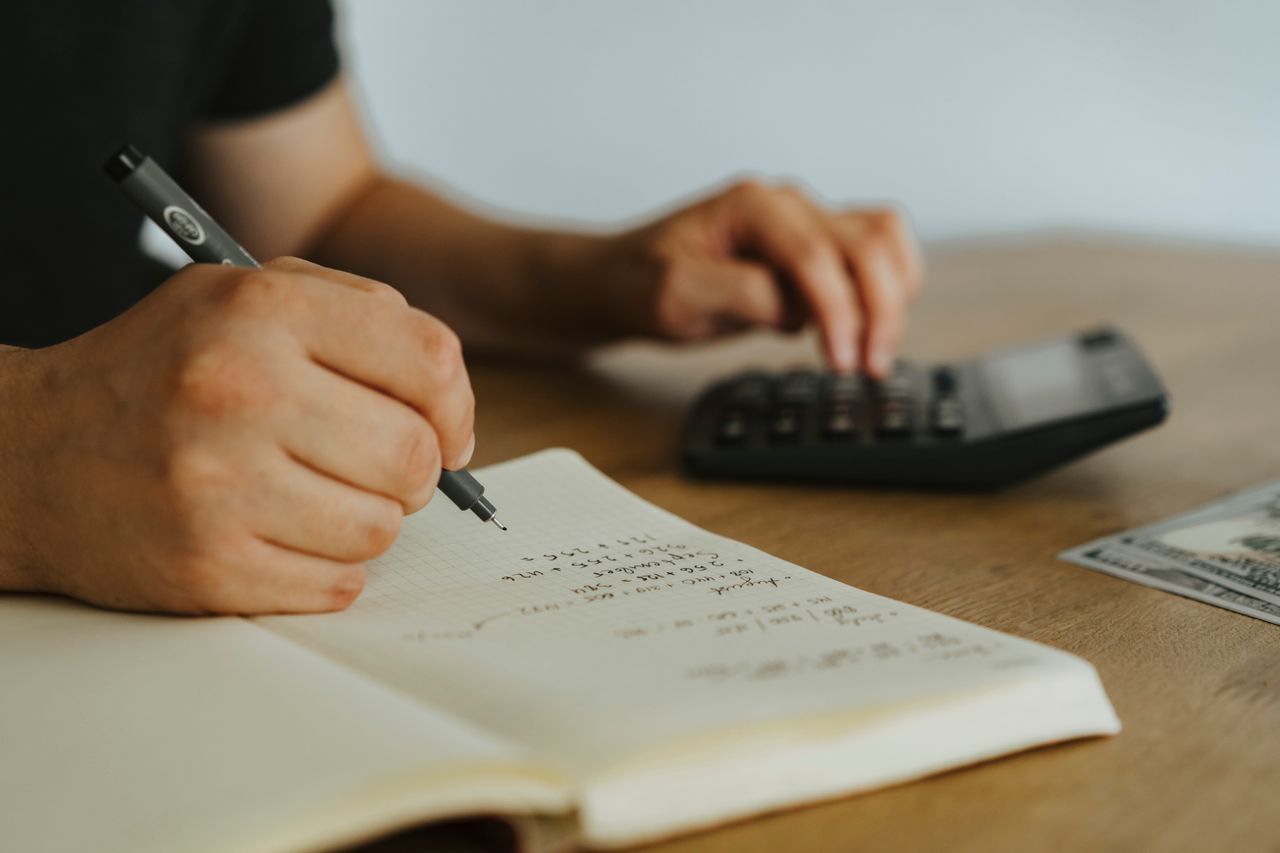 Persona anotando sus gastos a mano en un cuaderno para llevar el registro de su presupuesto personal
