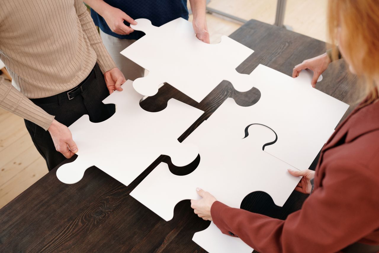 4 personas sosteniendo cada uno una pieza de puzzle que representa el cuadrante del flujo de dinero de Robert Kiyosaki