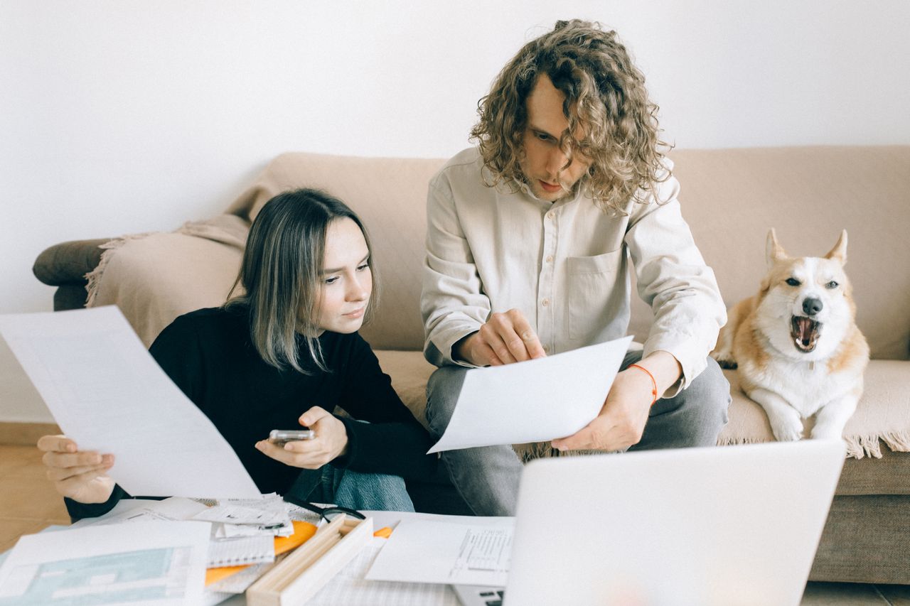 Pareja revisando papeles y finanzas desordenadas en casa, reflejando la falta de un presupuesto formal