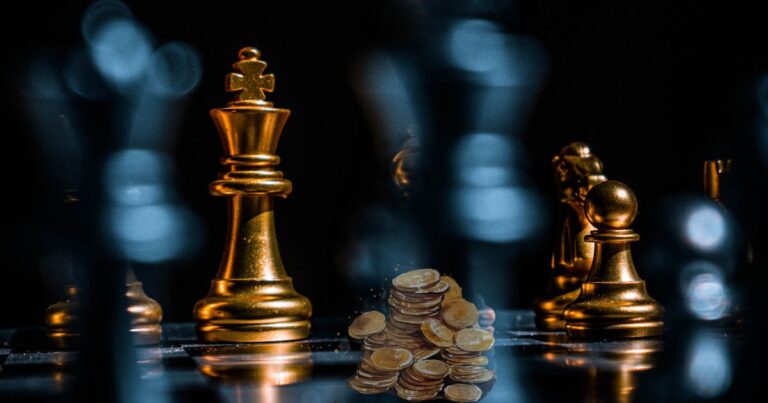 Rey de ajedrez dorado junto a una pila de monedas sobre un tablero, representando las reglas para ganar el juego del dinero